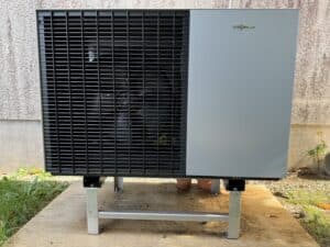 Unité extérieure de pompe à chaleur Viessmann grise et noire installée sur un socle métallique dans un jardin.